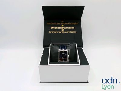 an open box with a watch inside of it on a white surface