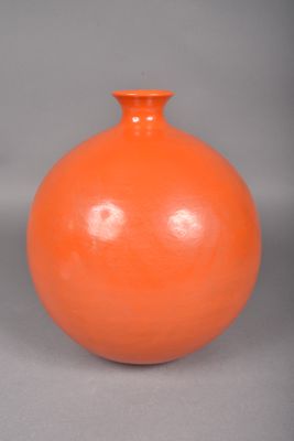 un vase orange posé sur une surface grise