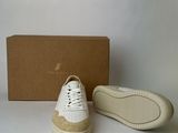 pair of white sneakers with tan soles on white surface next to box