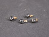 un gros plan sur quatre boucles d'oreilles à clous noires et dorées posées sur une surface noire