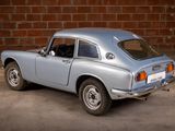 an image of a blue car parked in front of a brick wall