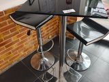 une table noire avec deux tabourets noirs devant un mur de briques