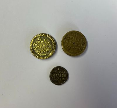 trois pièces d'or posées sur une surface blanche