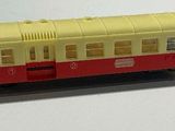 a toy train on a white surface with a red and yellow car