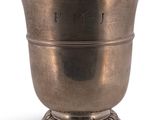 une coupe en argent ancien posée sur un socle, sur fond blanc