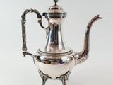 an antique silver tea pot with a handle on a stand