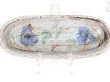 une assiette blanche décorée de fleurs bleues, posée sur un socle