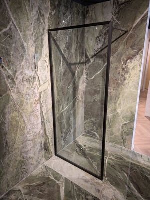 une porte de douche en verre dans un coin de la salle de bains