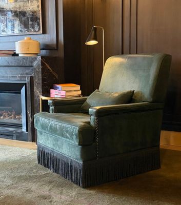 a green chair sitting in front of a fireplace in a living room
