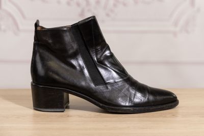 black leather ankle boots with zippers on a wooden table
