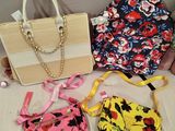 three purses and a handbag sitting on a bed