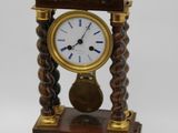 a small clock that is on a stand on a white background