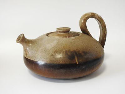 une théière marron et noire posée sur une surface blanche