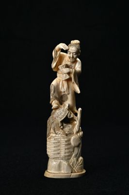 Figurine chinoise en ivoire sculpté représentant un ange et un oiseau posés sur un panier