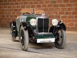 a old green car parked in front of a brick wall