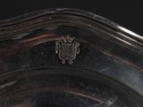an antique silver plate with a coat of arms on the top of it