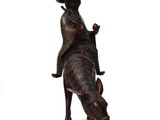 a statue of a man riding a cow with a hat on