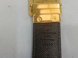 someone is holding a gold watch with a black leather strap