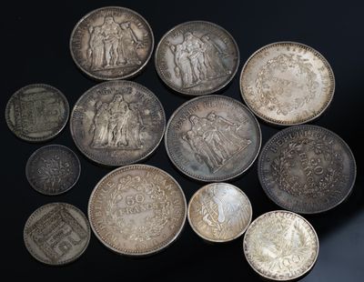 Plusieurs pièces d'argent sont disposées en cercle sur une surface noire