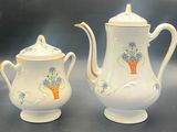 two white teapots with flowers on them on a table