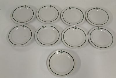 twelve white and black dinner plates with black rims on a white table