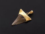 a close up of a gold pendant with a knife on a black surface