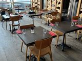 tables and chairs in a restaurant with a large window in the background
