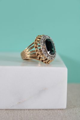gros plan d'une bague en or avec une pierre verte