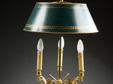 an antique brass table lamp with a green shade and three candles