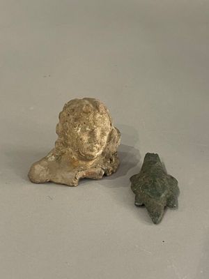une petite statue représentant une femme et une flèche en pierre