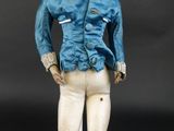 une poupée qui porte une veste bleue et un pantalon blanc