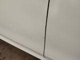 the side of a white car with a crack in the door