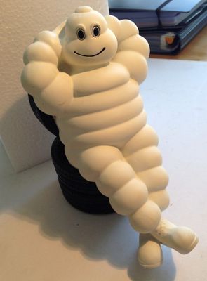 une petite figurine blanche représentant un personnage de dessin animé assis sur un pneu