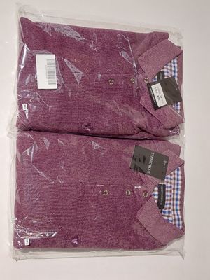 two purple shirts wrapped in plastic on top of a white table