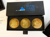 trois pièces d'or dans une boîte noire posée sur une table