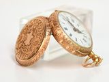 a gold pocket watch sitting on top of a glass block