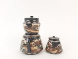 two black and white vases with designs on them on a white surface