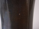 a black vase with a brown base on a table