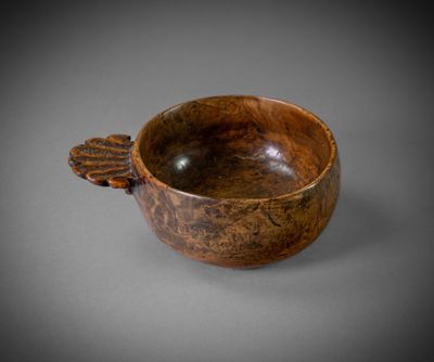 an old wooden bowl with a leaf handle on a gray surface