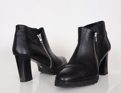paire de bottines en cuir noir avec fermetures éclair sur fond blanc