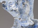 a blue and white ceramic sculpture of a woman holding a bird