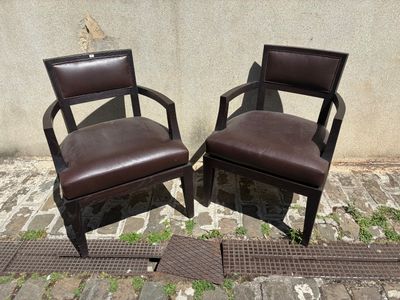deux chaises marron placées l'une à côté de l'autre dans une rue pavée