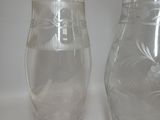 two glass vases sitting on a table next to each other