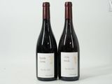 two bottles of red wine sitting next to each other on a white surface
