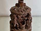 a small vase with a statue on it on a glass table