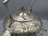a silver teapot with a handle and a handle on top of it