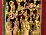 a gold sculpture of a group of people on a red surface