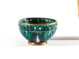 un bol vert et bleu posé à côté d'un vase jaune