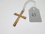 une croix en or et une étiquette de prix posées sur une table blanche