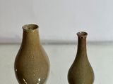 deux petits vases posés l'un à côté de l'autre sur une table